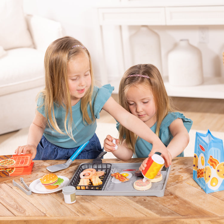 A kid playing with The Melissa & Doug Flip & Fry Grill Play Set with Water WOW!® Color Changing Play Food Preschool Toy Ages 3+
