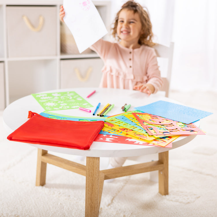 A kid playing with The Melissa & Doug Created by Me! Stencil Art Coloring Activity Kit in Storage Pouch -- 170+ Designs, 6 Markers, 2 Crayons, Paper