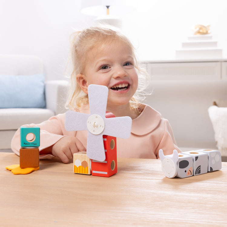 A kid playing with The Melissa & Doug Blockables™ Farm and Farm Friends 2-Pack Bundle Connectable Wooden Building Blocks Preschool Play Set Toy