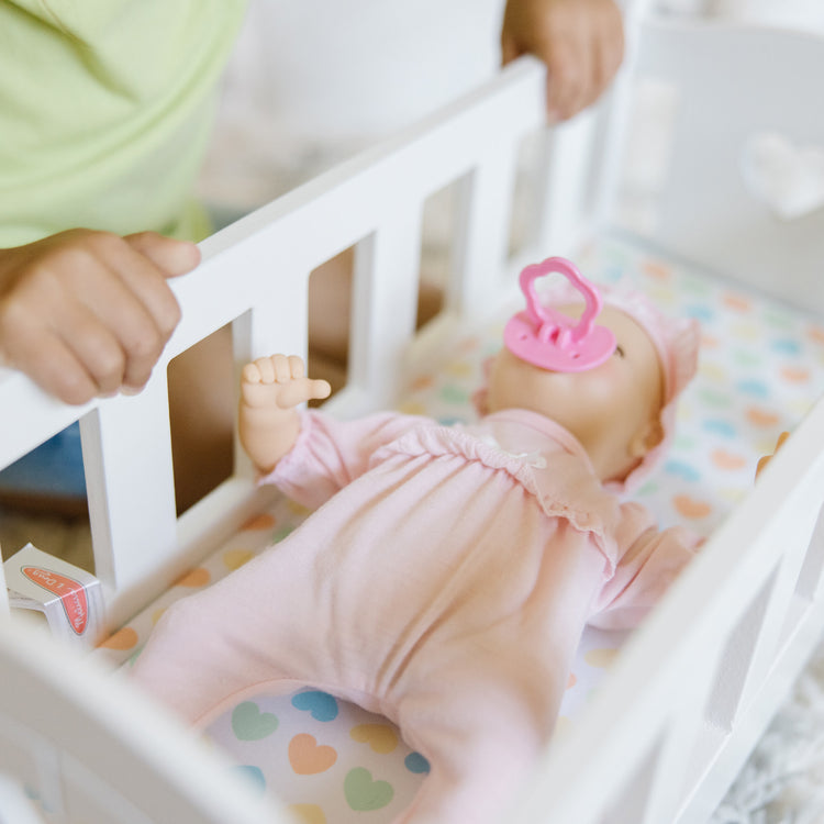 A kid playing with The Melissa & Doug Mine to Love Wooden Play Cradle for Dolls, Stuffed Animals - White