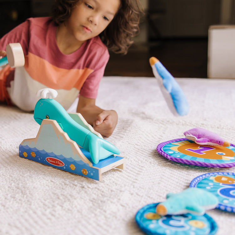 A kid playing with The Melissa & Doug Fun at the Fair! Penguin Launch Game