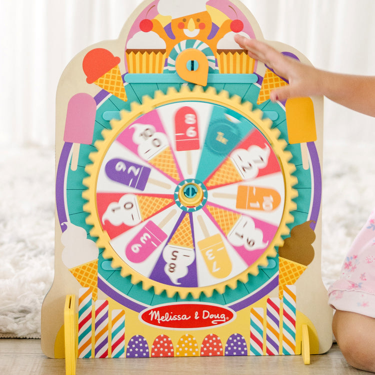 A kid playing with The Melissa & Doug Fun at the Fair! Wooden Double-Sided Roulette & Plinko Games