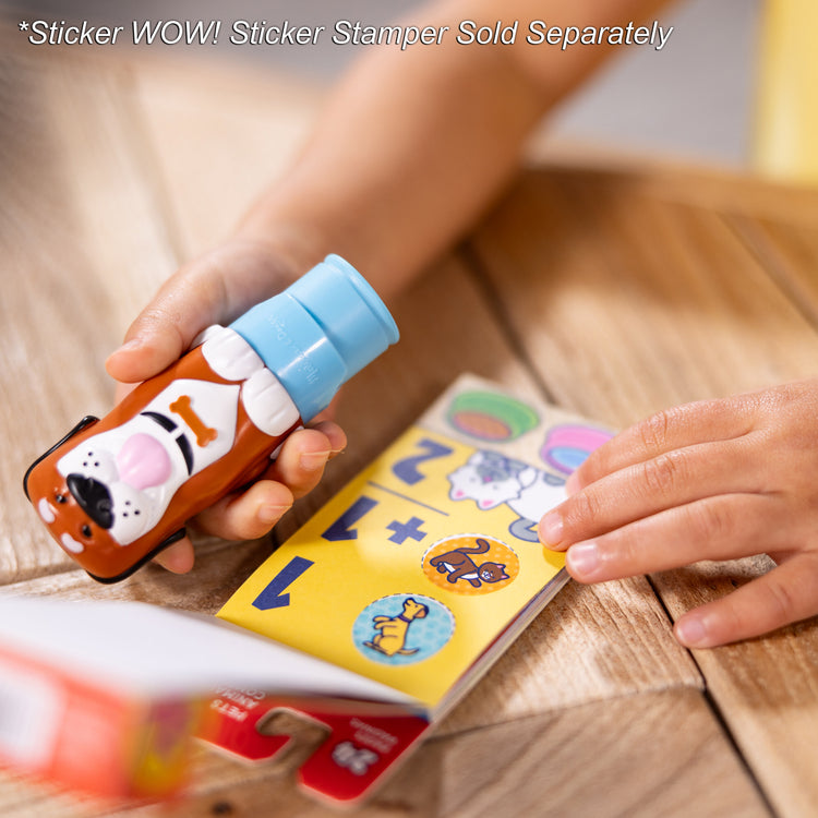 A kid playing with The Melissa & Doug Sticker WOW!™ Mini Activity Pad and 200+ Refill Stickers for Sticker Stamper Arts and Crafts Fidget Toy Collectibles – Pets Stickers