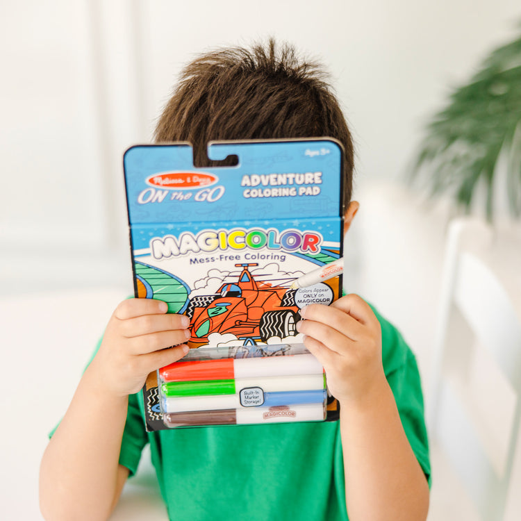 A kid playing with The Melissa & Doug On the Go Magicolor Coloring Pad: Adventure - 18 Coloring Pages and 4 Markers
