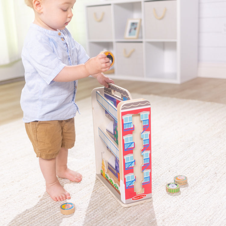 A kid playing with The Melissa & Doug GO Tots Wooden Town House Tumble with 6 Disks