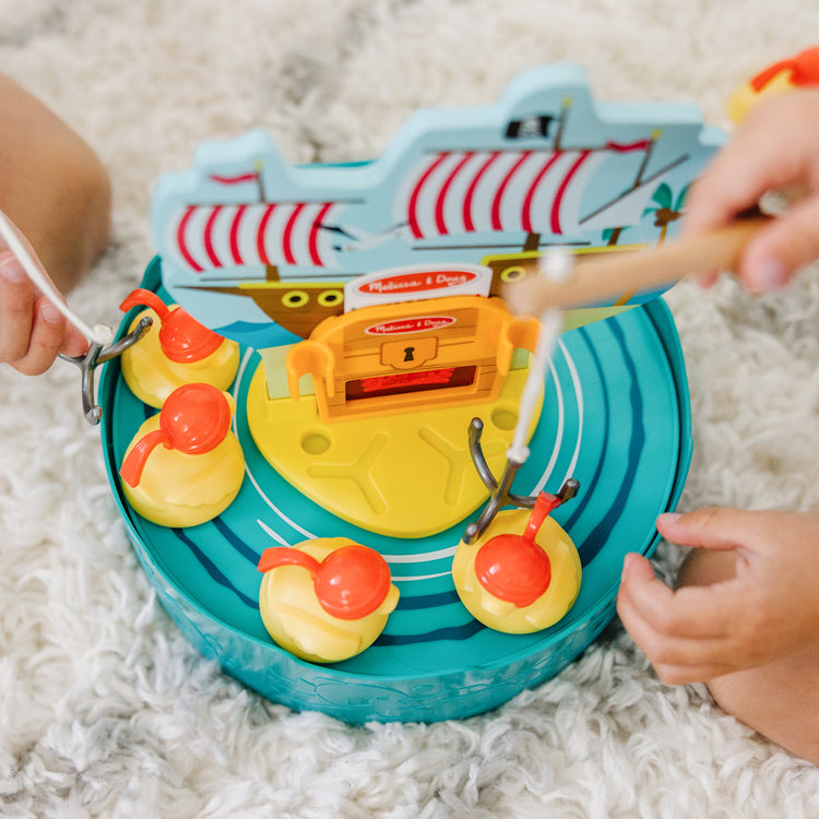 A kid playing with The Melissa & Doug Fun at the Fair! Hook a Duck Pirate Fishing Game