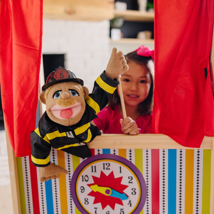 A kid playing with The Melissa & Doug Deluxe Puppet Theater - Sturdy Wooden Construction