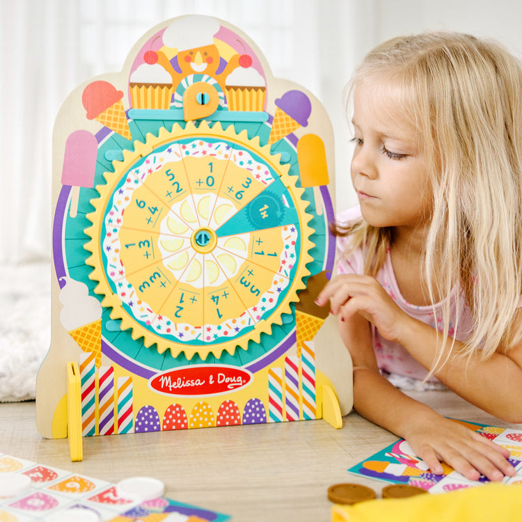 A kid playing with The Melissa & Doug Fun at the Fair! Wooden Double-Sided Roulette & Plinko Games