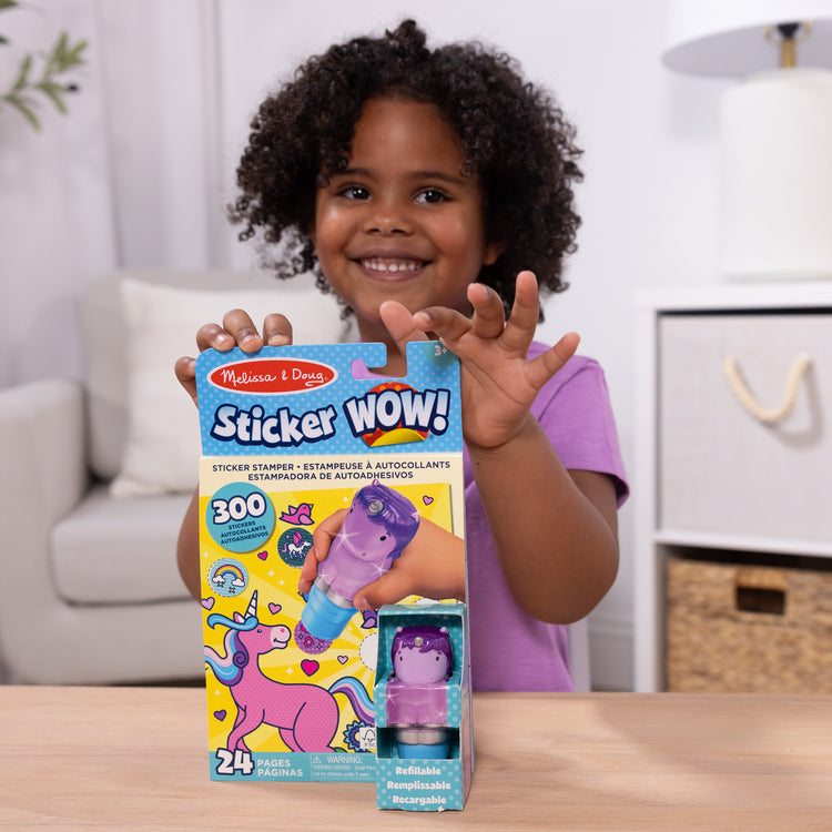 A kid playing with The Melissa & Doug Sticker WOW!™ 24-Page Activity Pad and Sticker Stamper, 300 Stickers, Arts and Crafts Fidget Toy Collectible Character – Sprinkles the Purple Unicorn
