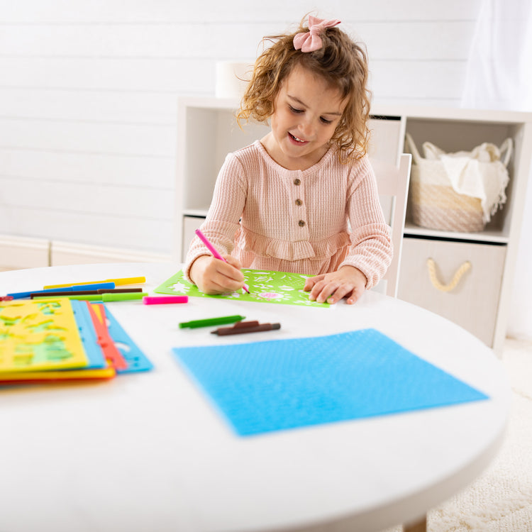 A kid playing with The Melissa & Doug Created by Me! Stencil Art Coloring Activity Kit in Storage Pouch -- 170+ Designs, 6 Markers, 2 Crayons, Paper