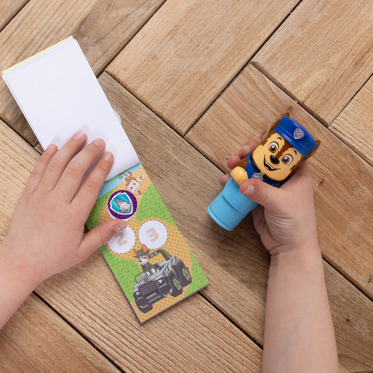 A kid playing with The Melissa & Doug Sticker WOW!™ Mini Activity Pad and 200+ Refill Stickers for Sticker Stamper Arts and Crafts Fidget Toy Collectibles – PAW Patrol Stickers