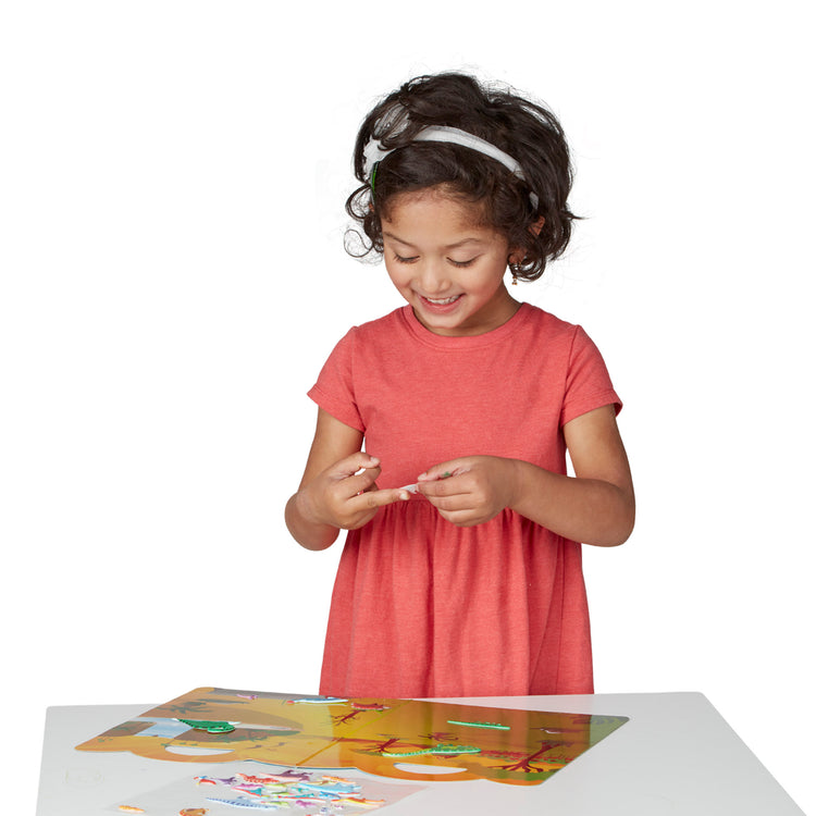 A child on white background with The Melissa & Doug Reusable Puffy Sticker Wild Adventures Play Set 3-Pack (118 Stickers: Safari, Dinosaur, Ocean)