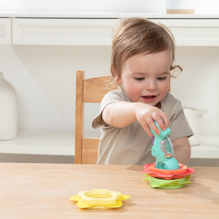 A kid playing with The Melissa & Doug Ocean Waves Press & Stack Seahorse Stacking Toy with 3 Sensory Rings - Rattle for Babies 10 Months+