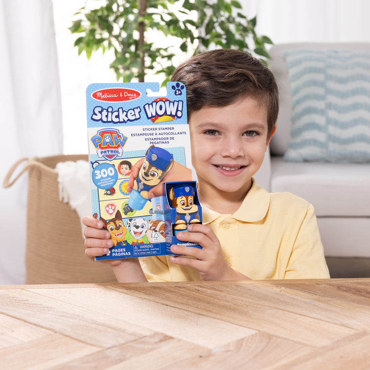 A kid playing with The Melissa & Doug Sticker WOW!™ 24-Page Activity Pad and Sticker Stamper, 300 Stickers, Arts and Crafts Fidget Toy Collectible Character – PAW Patrol Chase
