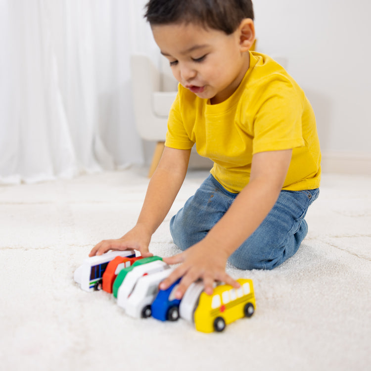 A kid playing with The Melissa & Doug Wooden Town Vehicles Set in Wooden Tray (9 pcs)