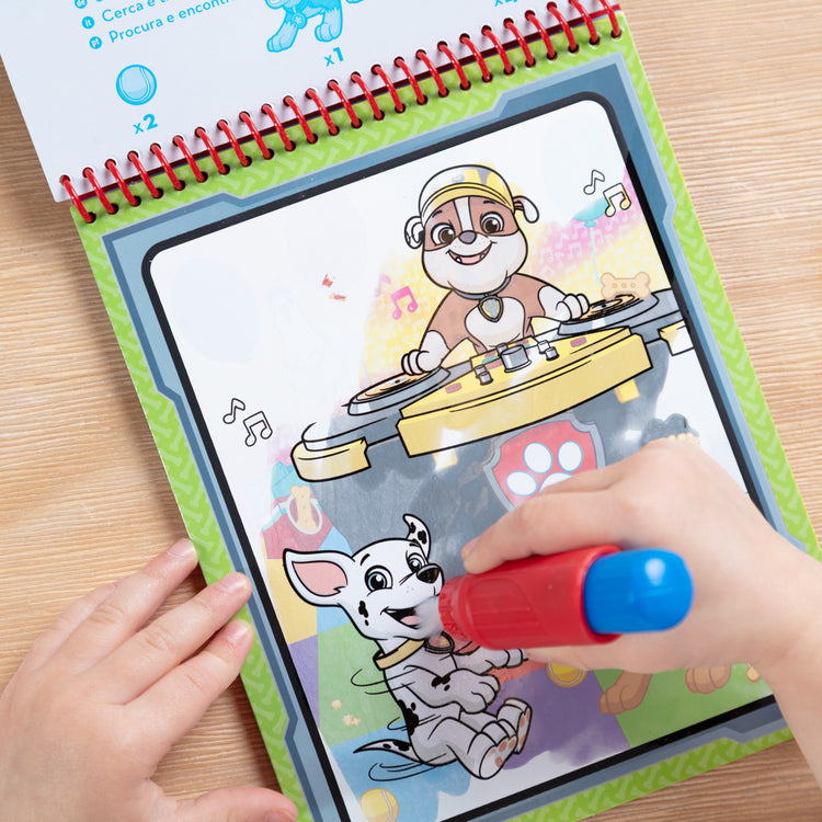 A kid playing with The Melissa & Doug Water WOW! PAW Patrol Marshall Reusable Coloring Book with Refillable Water Pen - For Ages 3+