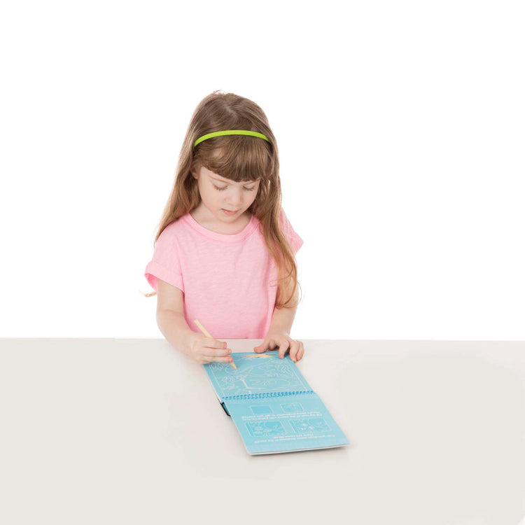 A child on white background with The Melissa & Doug On the Go Scratch Art Sea Life Color-Reveal 12-Page Activity Pad Creative Play for Boys and Girls Ages 5+