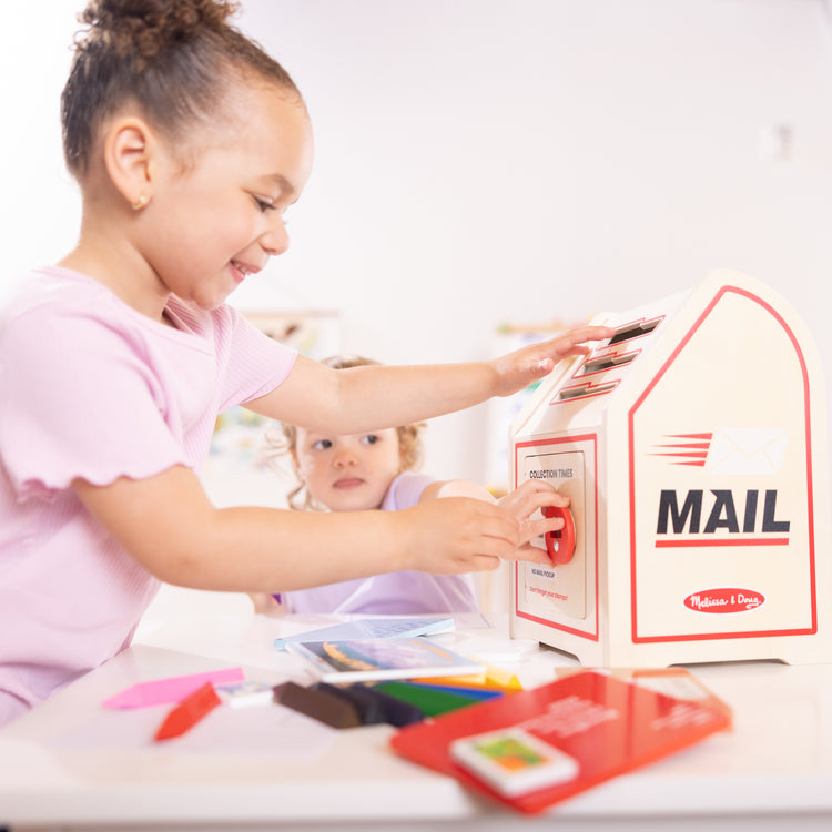 A kid playing with The Stamp and Sort Mailbox Play Set