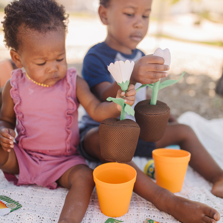A kid playing with The Melissa & Doug Let’s Explore Flower Gardening Play Set with Color-Changing Flowers (16 Pieces)