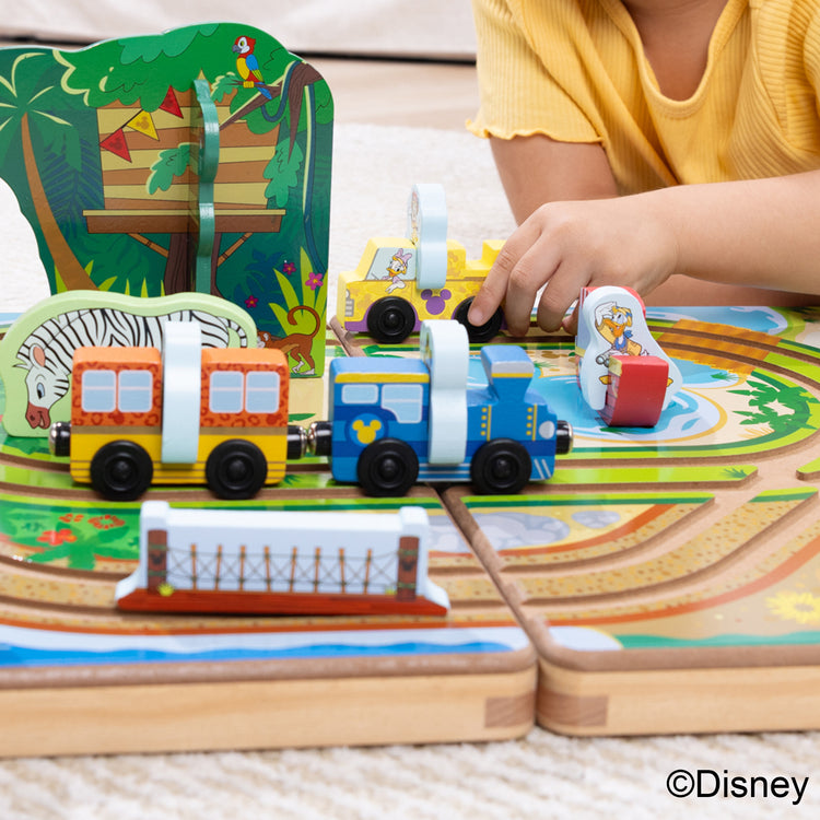 A kid playing with The Melissa & Doug Disney Take-Along Safari Adventure Wooden Play Set with Built-In Tracks – 20 Pieces | Mickey Mouse, Minnie, Wooden Toy for Boys and for Girls 3+