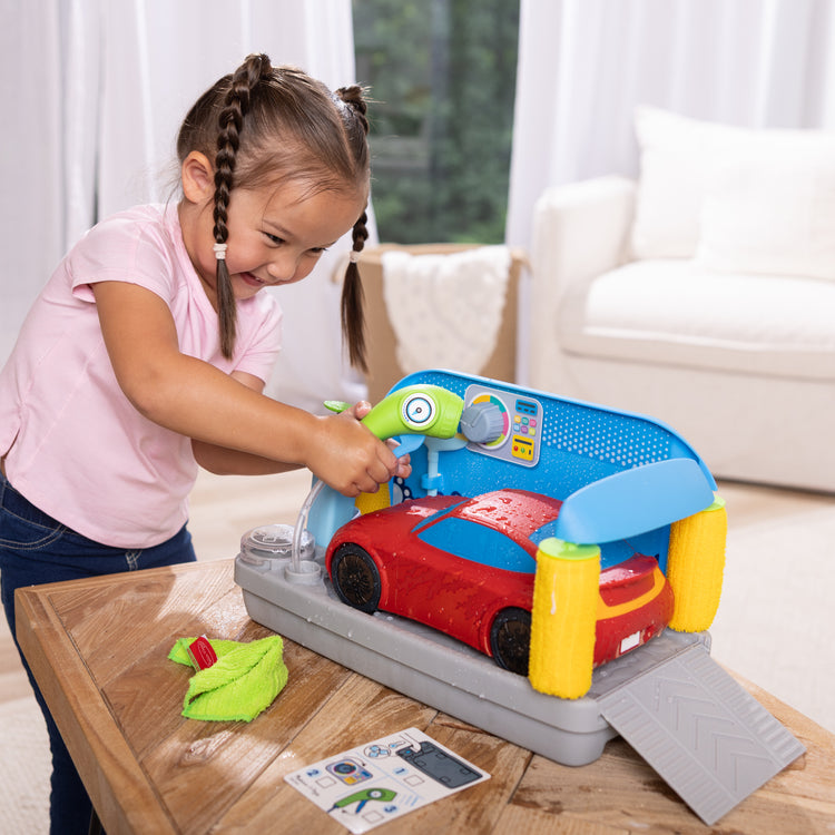 A kid playing with The Melissa & Doug Spray & Shine Car Wash Color-Changing Water Toy Play Set Boys and Girls 3+