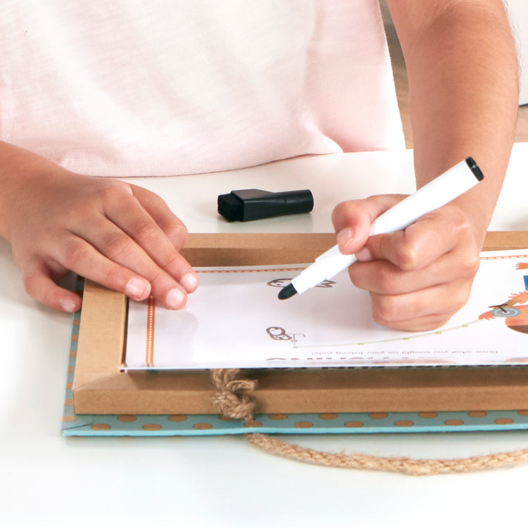 A kid playing with The Melissa & Doug Natural Play: Play, Draw, Create Reusable Drawing & Magnet Kit – Ocean (42 Magnets, 5 Dry-Erase Markers)