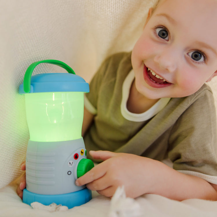 A kid playing with The Melissa & Doug Let’s Explore™ Light & Sound Camping Lantern Play Set