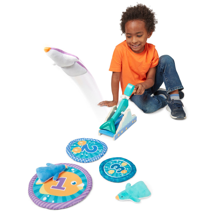A kid playing with The Melissa & Doug Fun at the Fair! Penguin Launch Game