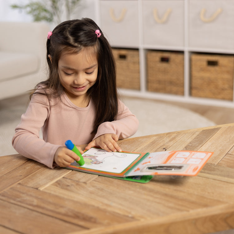 A kid playing with The Melissa & Doug On the Go Water Wow! Reusable Water-Reveal Coloring Activity Pad Travel Toy for Boys and Girls– Jungle