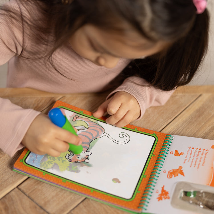 A kid playing with The Melissa & Doug On the Go Water Wow! Reusable Water-Reveal Coloring Activity Pad Travel Toy for Boys and Girls– Jungle