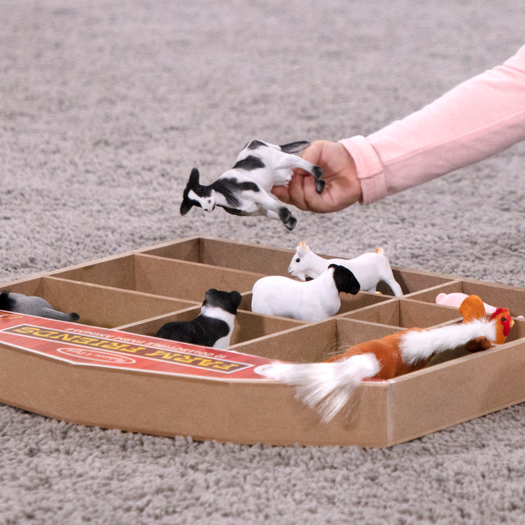 A kid playing with The Melissa & Doug Farm Friends Collectible Toy Animal Figures (10 pcs)