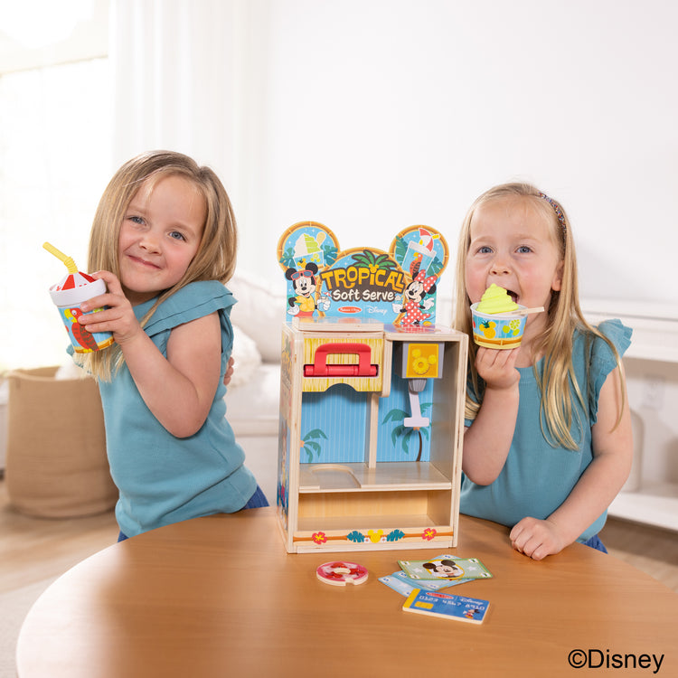 A kid playing with The Disney Tropical Soft Serve Ice Cream Wooden Play Food Set – 23 Pieces | Mickey Mouse, Minnie, Wooden Toy for Boys and for Girls 3+