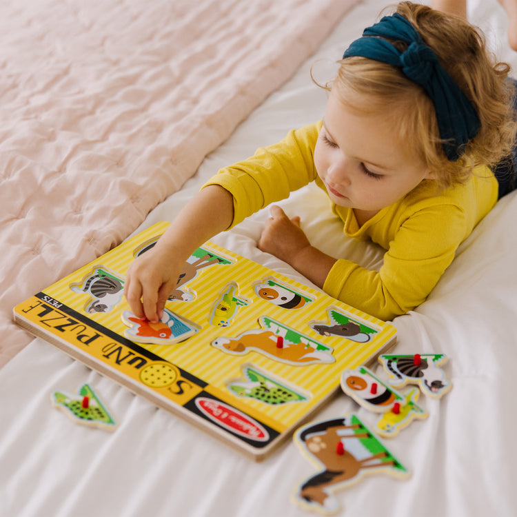 A kid playing with The Melissa & Doug Pets Sound Puzzle - Wooden Peg Puzzle With Sound Effects (8 pcs)