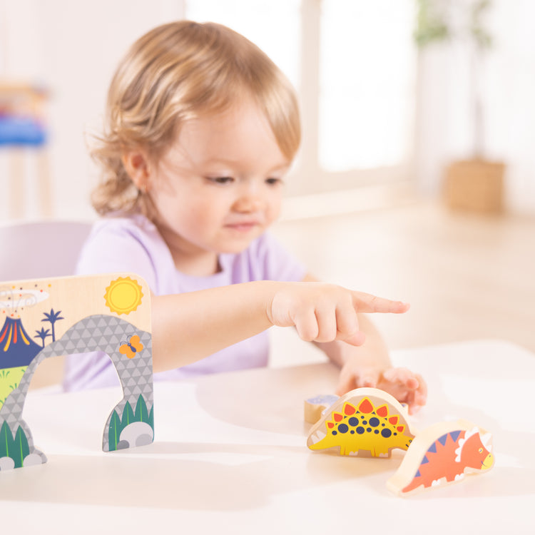 A kid playing with The Wooden Dinosaurs Play Set