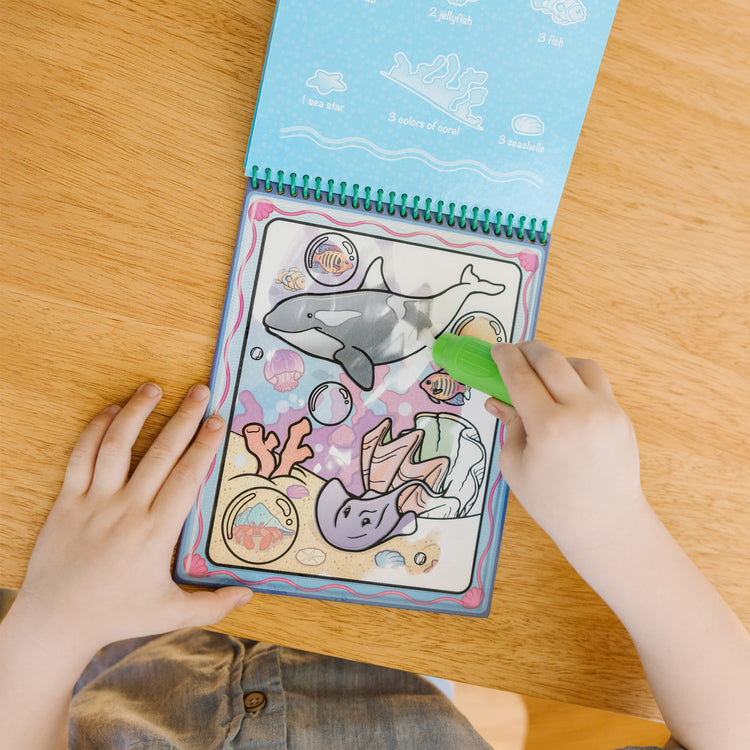A kid playing with The Melissa & Doug On the Go Water Wow! Reusable Color with Water Activity Pad 3-Pack, Jungle, Safari, Farm