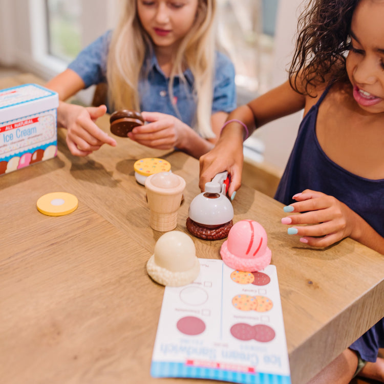 A kid playing with The Melissa & Doug Scoops and Sandwiches 13-Piece Ice Cream Play Food Set