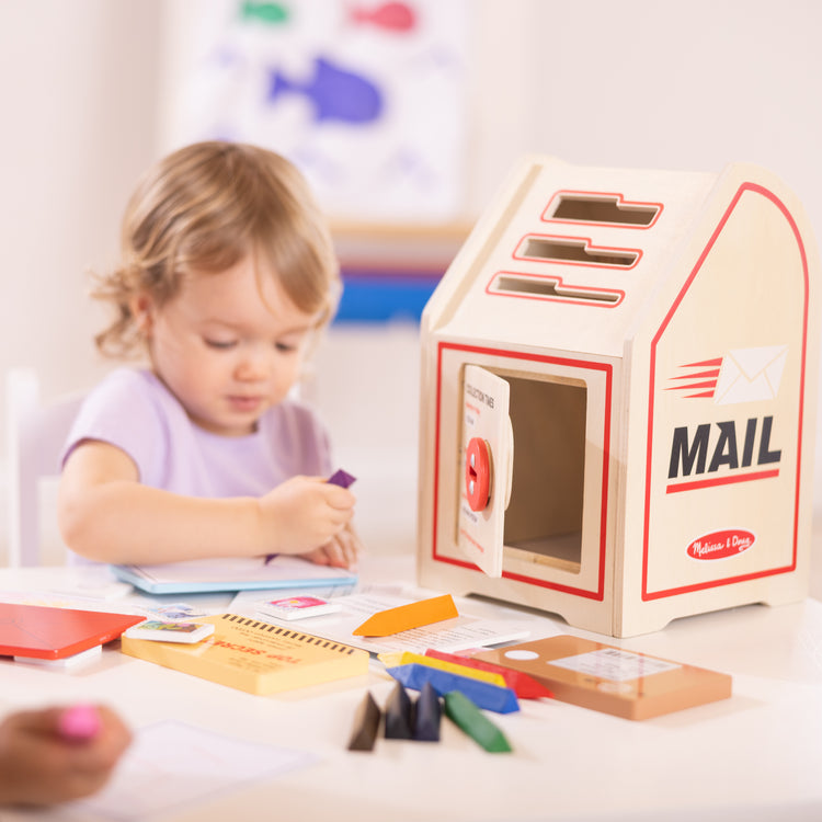 A kid playing with The Stamp and Sort Mailbox Play Set