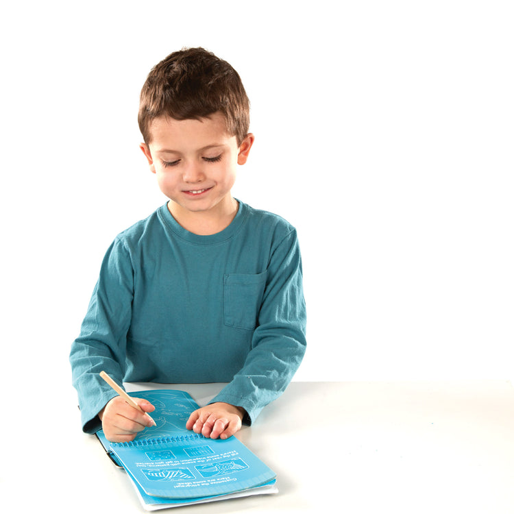 A child on white background with The Melissa & Doug On the Go Scratch Art Sea Life Color-Reveal 12-Page Activity Pad Creative Play for Boys and Girls Ages 5+