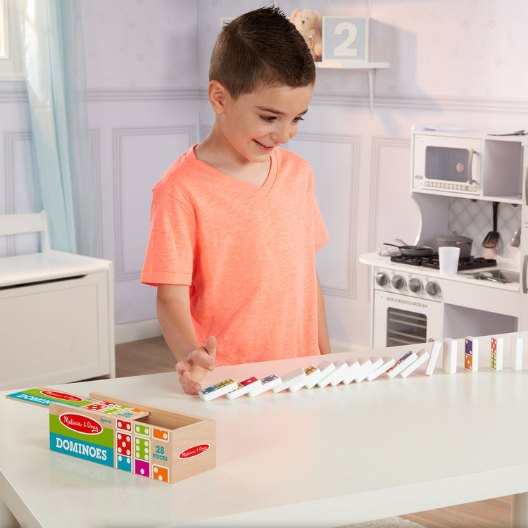 A kid playing with The Melissa & Doug Dominoes Tabletop Game with 28 Colorful Tiles in Wooden Storage Box