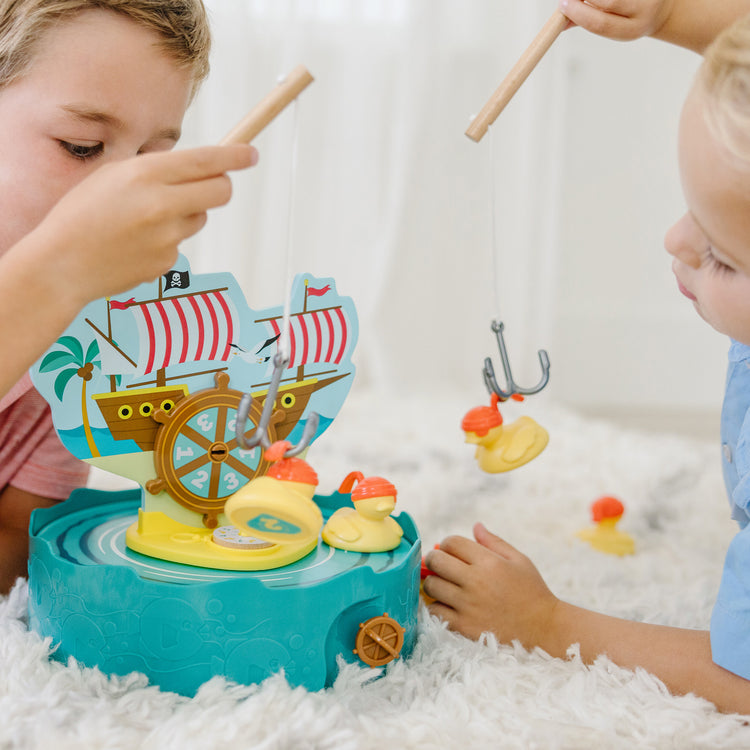 A kid playing with The Melissa & Doug Fun at the Fair! Hook a Duck Pirate Fishing Game