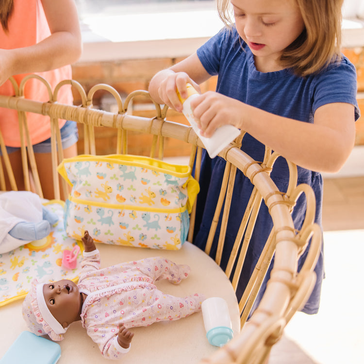A kid playing with The Melissa & Doug Mine to Love Travel Time Play Set for Dolls with Diaper Bag, Bottle, Sunscreen, More (17 pcs)