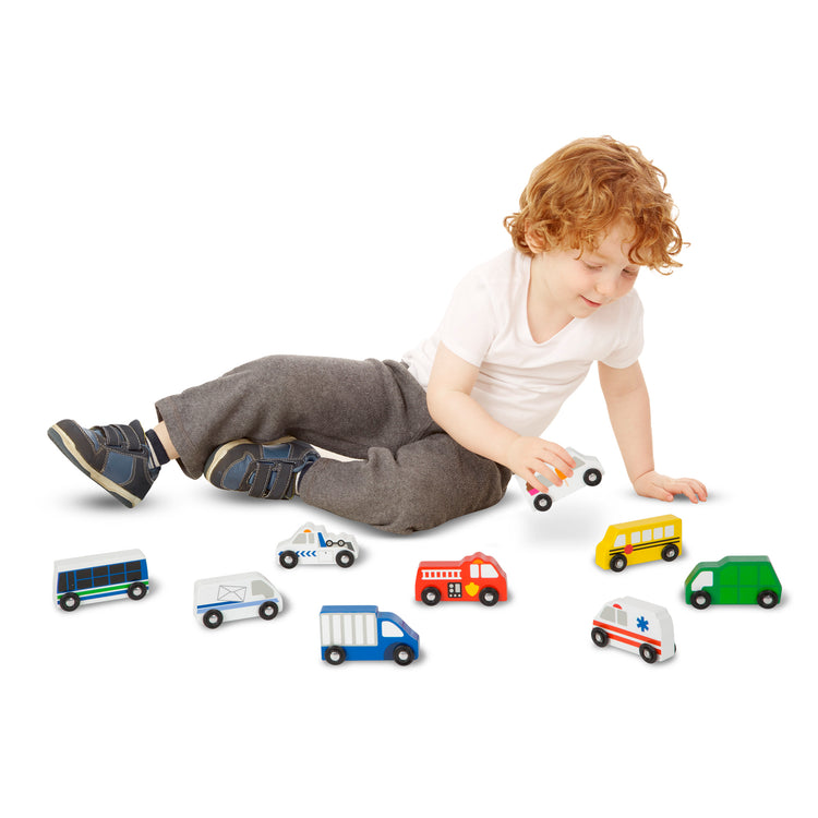 A child on white background with The Melissa & Doug Wooden Town Vehicles Set in Wooden Tray (9 pcs)