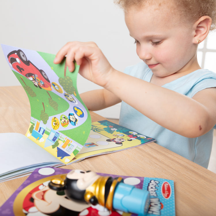 A kid playing with The Melissa & Doug Sticker WOW! Disney Special Edition Pack with Mickey & Minnie Stampers and 900 Stickers - Ages 3+