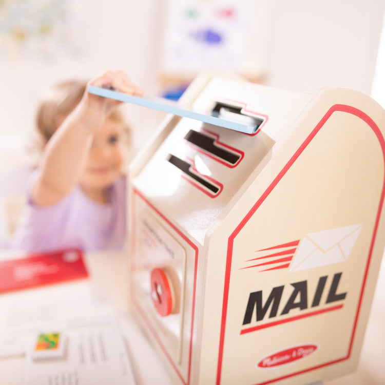 A kid playing with The Stamp and Sort Mailbox Play Set