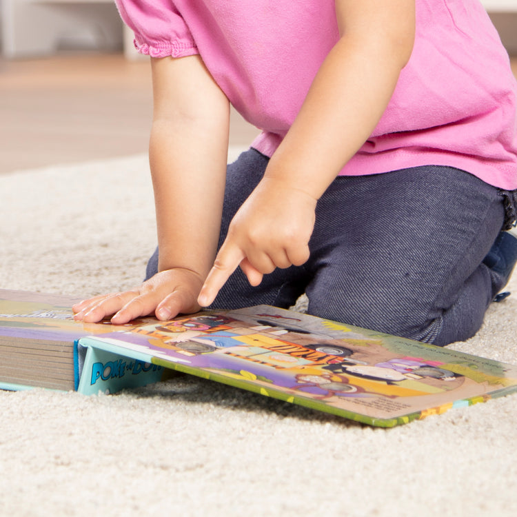 A kid playing with The Melissa & Doug Children's Book - Poke-a-Dot: The Wheels on the Bus Wild Safari (Board Book with Buttons to Pop)
