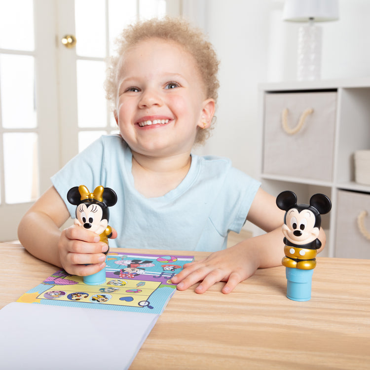 A kid playing with The Melissa & Doug Sticker WOW! Disney Special Edition Pack with Mickey & Minnie Stampers and 900 Stickers - Ages 3+