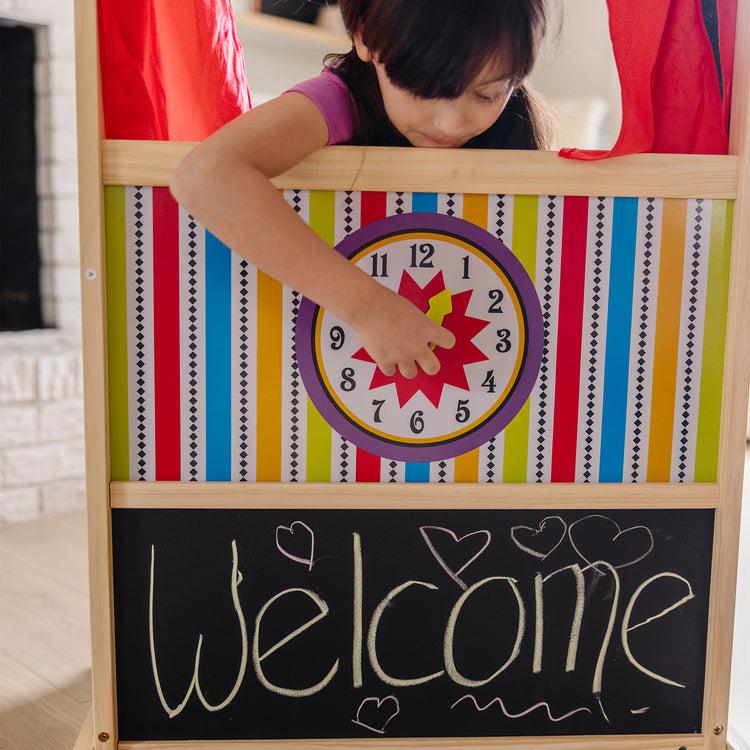 A kid playing with The Melissa & Doug Deluxe Puppet Theater - Sturdy Wooden Construction