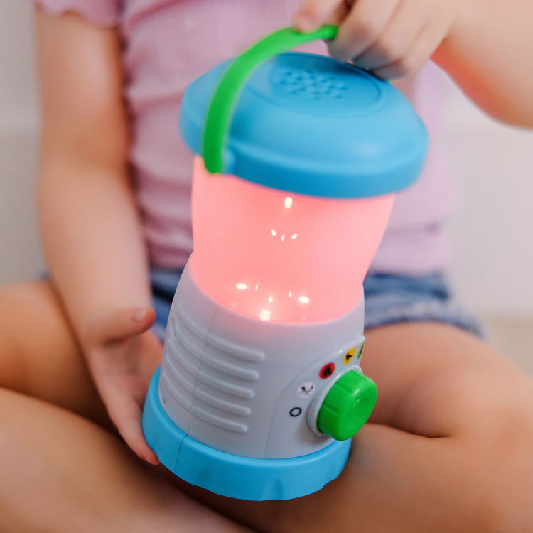 A kid playing with The Melissa & Doug Let’s Explore™ Light & Sound Camping Lantern Play Set