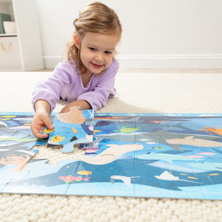 A kid playing with The Melissa & Doug Beneath the Waves, Ocean-Themed Search and Find Jumbo Floor Puzzle, 48-Piece Jigsaw Puzzle with Learning Activity, Over 4 Ft Long, Kids Puzzles for Girls & Boys Ages 3 and Up