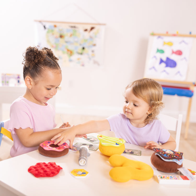 A kid playing with The Melissa & Doug Disney Fill and Top Donut Play Set with 4 Squishy Donuts and Wooden Toppings - For Ages 3+